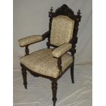 A Victorian carved beech open arm occasional chair upholstered in figure and floral fabric on