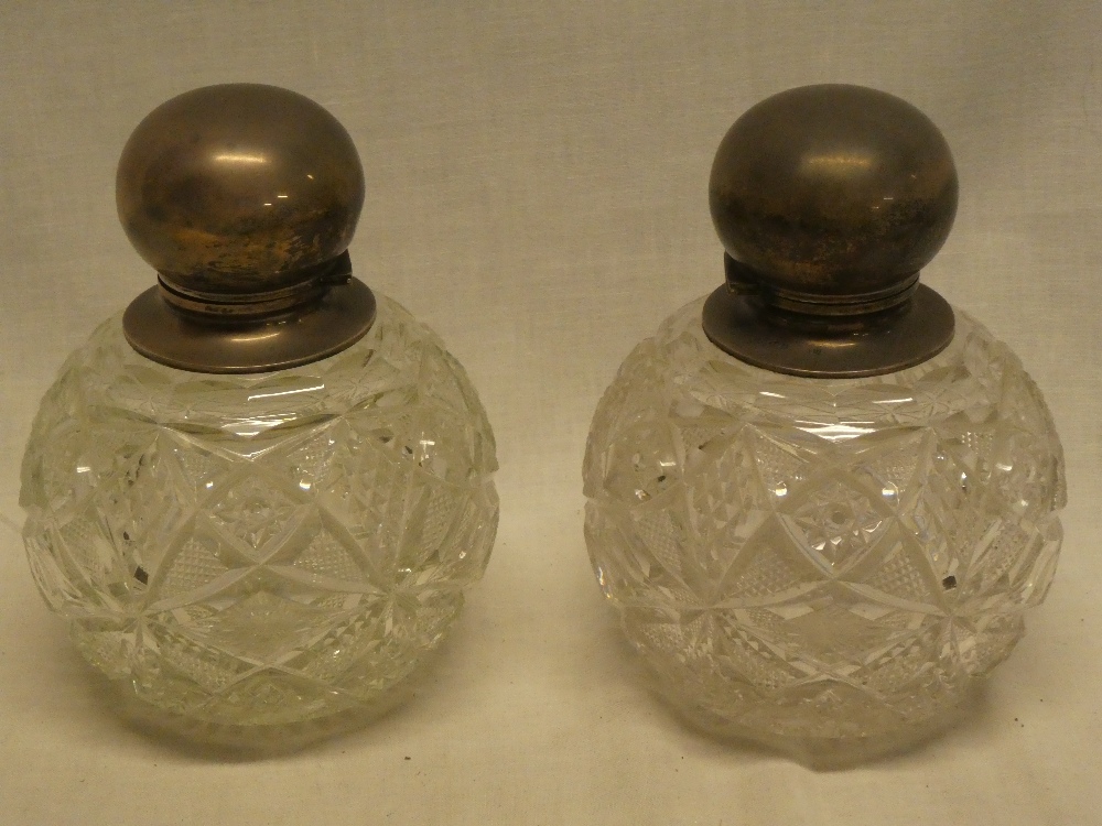 A pair of large good quality cut glass spherical scent bottles with silver mounted necks and hinged