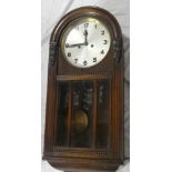 A good quality 1930's oak wall clock with silvered circular dial in arched glazed case