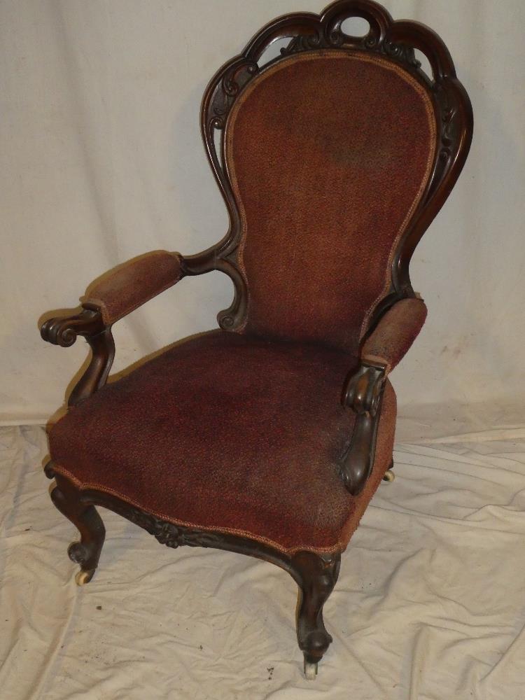 A Victorian carved mahogany open arm easy chair upholstered in fabric on scroll shaped legs with
