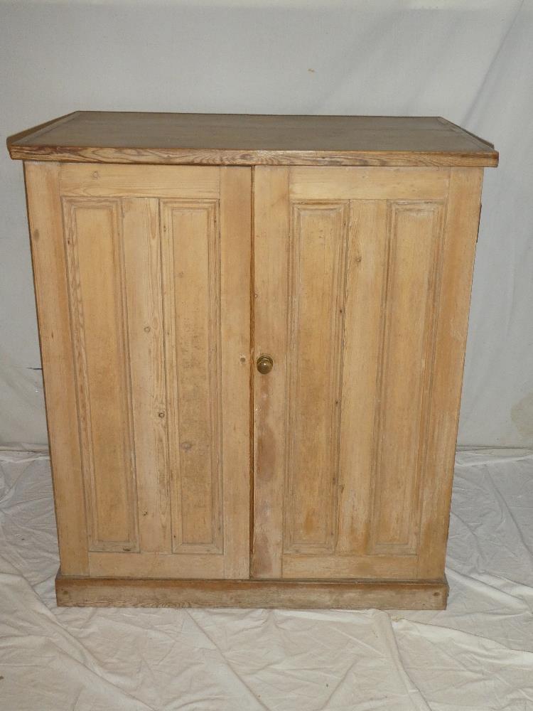 An old polished pine cupboard with shelves enclosed by two panelled doors 42" high x 37" wide