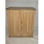 An old polished pine cupboard with shelves enclosed by two panelled doors 42" high x 37" wide