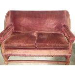 A late Victorian wing open arm two seat sofa upholstered in red fabric with loose cushions 56" long