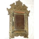 An unusual brass embossed rectangular cushion-framed mirror with raised scroll decoration 26" long