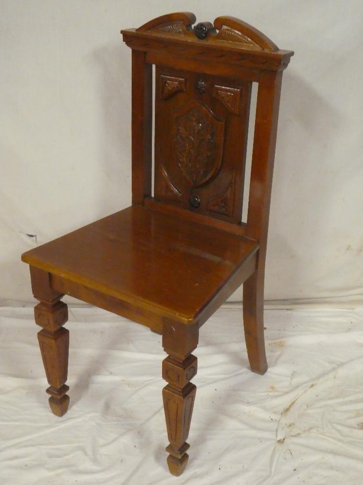 An Edwardian walnut hall chair, the rectangular panelled back with carved floral shield,