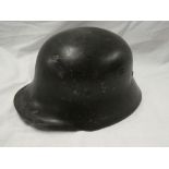 An old German black painted steel combat helmet with liner and chin strap