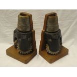 A pair of unusual wooden and iron bookends constructed from half-sectioned mining drill bits