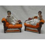 A pair of Victorian Staffordshire pottery figures of a male and female reclining on settees