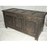 An 18th century carved oak rectangular coffer with triple panelled front and hinged lid on block