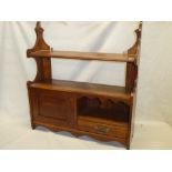 An Edwardian oak wall mounted open shelf with single drawer and cupboard enclosed by a small