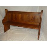 A small polished pine pew on standard supports,