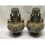 A pair of 19th Century Majolica glazed two-handled tapered vases with raised foliage and mask head