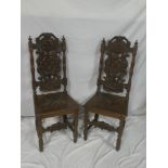 A pair of 19th century Continental carved oak hall chairs with elaborate decorated backs and carved