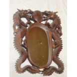 A 20th Century Chinese-style oval mirror in carved teak dragon decorated frame,