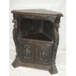 A Victorian carved oak corner cabinet with open recess above a cupboard enclosed by two decorated