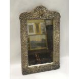 A late Victorian silver framed rectangular dressing mirror with raised scroll decoration,