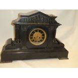 A large 19th century mantel clock with decorated circular dial in polished black slate
