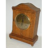 An American mantel clock with brass circular dial in oak arched case