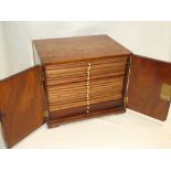 An old mahogany coin collector's cabinet with numerous shallow drawers and two base deeper drawers