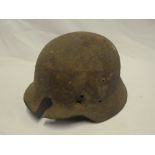 An original German Second War steel combat helmet in relic condition with battle damage