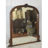 An old arched over-mantel mirror in carved and stained wood frame with scallop mount 56" x 45"