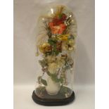 A Victorian display of artificial flowers within glass display dome on oval base,