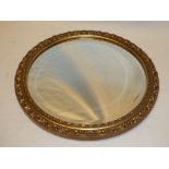 A bevelled circular wall mirror in ornate gilt frame,