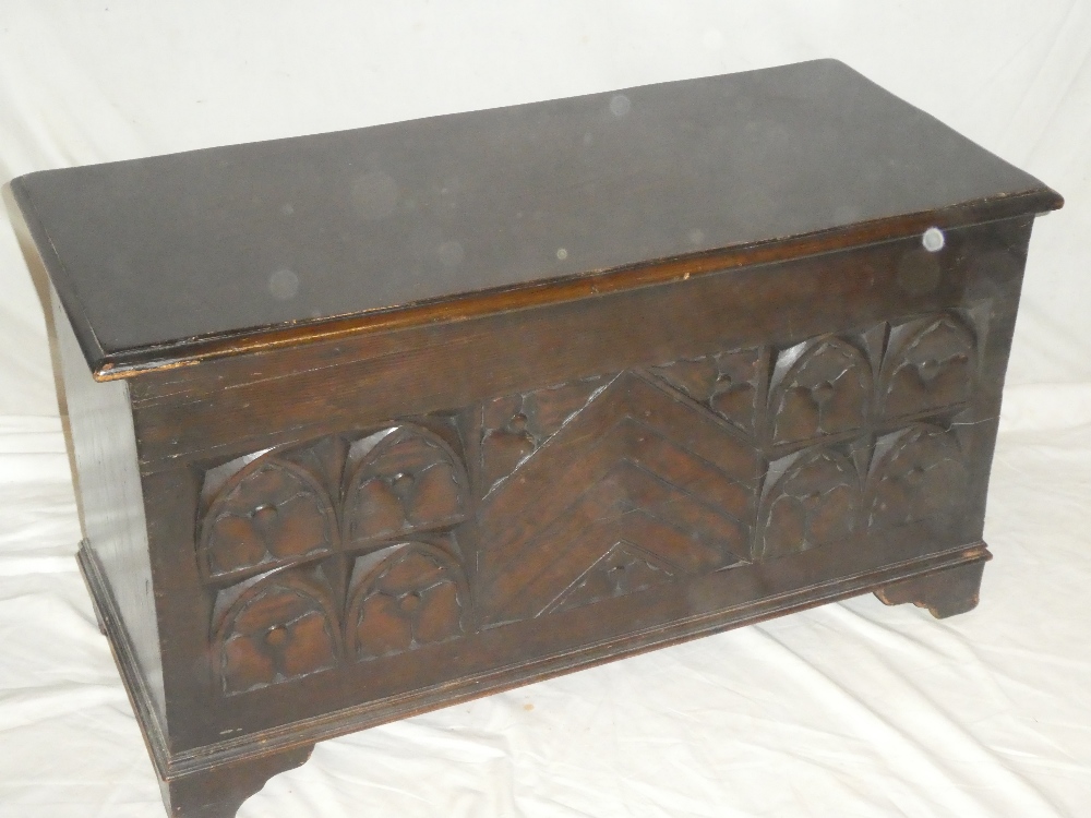 A good quality small carved oak rectangular coffer with decorated front and hinged lid on bracket