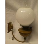 A wall mounted brass oil lamp by Hinks with curved bracket and opaque glass shade