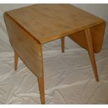 A 1960/70's Ercol pale elm drop leaf rectangular dining table on tapered legs
