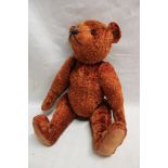 A plush covered straw filled teddy bear with pointed snout,