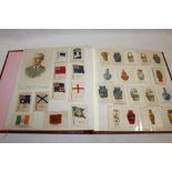 An album containing a collection of silk cigarette cards including flags, emblems, military etc.