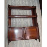 An Arts and Crafts oak three shelf wall hanging/table top two door cabinet with fret cut and metal