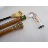 A collection of sticks to include a glass handled riding crop containing a yellow metal fox within