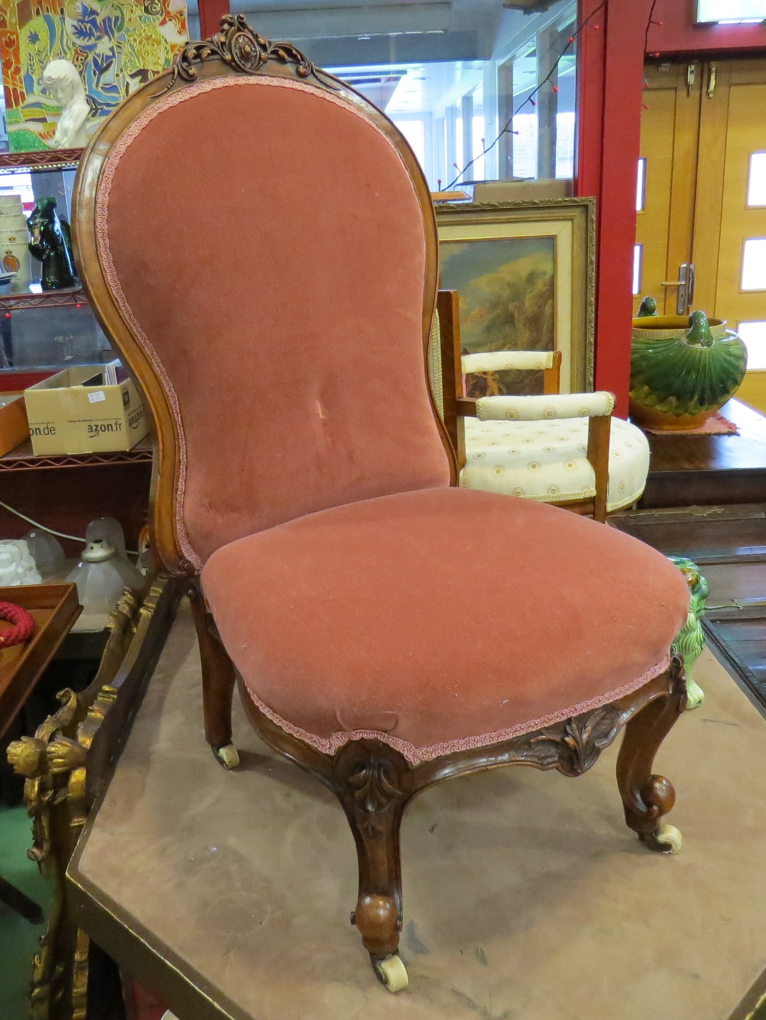 A circa 1850 carved walnut bedroom chair with pink upholstery on scroll feet and white ceramic