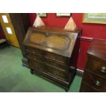 An oak bureau with geometric moulding decoration the fitted interior over three graduating long