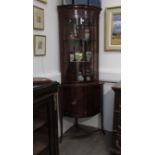 A circa 1830 mahogany bow fronted corner cabinet, glazed top over single door and drawer base,