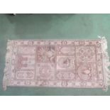 A beige ground Oriental rug with tasselled ends,