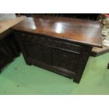 An 18th Century oak two panel coffer the hinged lid over a carved base on stile feet,