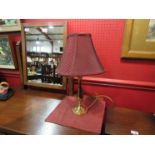 A brass table lamp with burgundy colour shade