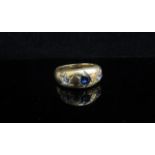 A gold ring centrally set with blue sapphire flanked by old cut diamonds in rubover star settings,