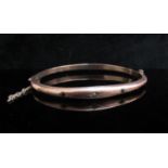 A 9ct rose gold bangle set with single diamond and sapphires, mis-shaped 6.