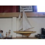 A wooden pond yacht with cloth sail, on stand,