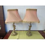 A pair of brass ormulu winged cherub table lamps on ornate rococo style base with pink tasselled