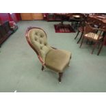 A circa 1860 walnut spoon-back armchair with carved floral decoration over a buttoned backrest and