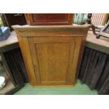 A George III oak wall hanging corner cupboard, panelled door, shelved interior, 94cm tall