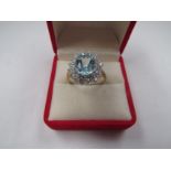 A 9ct gold dress ring with pale blue stone framed by clear stones. Size P, 3.9g
