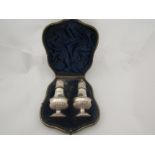 A leather cased pair of James Dixon & Sons Ltd silver pepperettes, one missing finial, 105g not