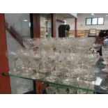 A collection of eight cut glass wine glasses and a quantity of sherry glasses