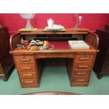 An Edwardian panelled oak tambour front twin pedestal desk the fitted interior over a central